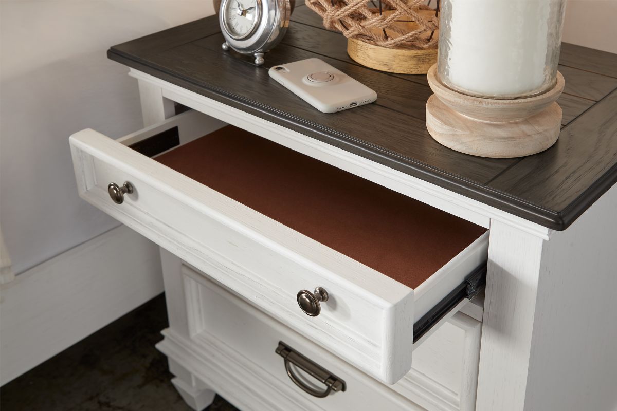 A front corner view of a white nightstand with a dark brown top and a drawer open