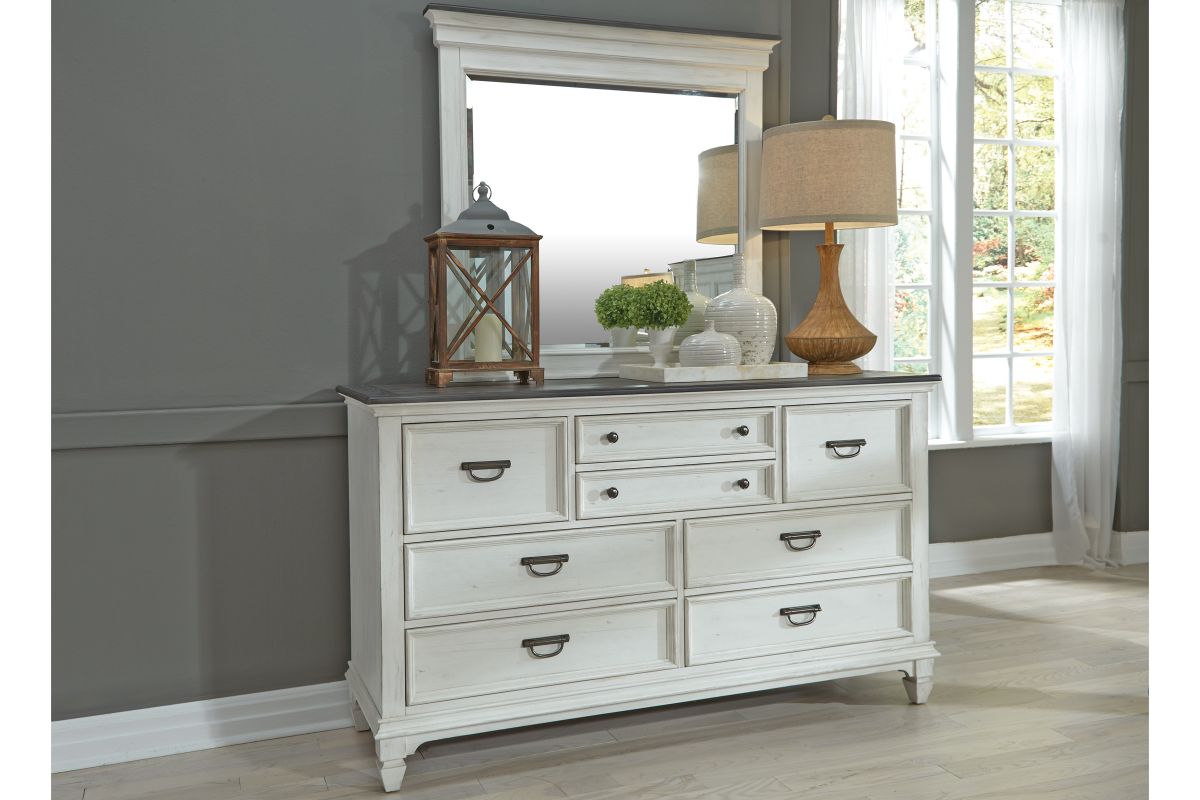 A white wood 8-drawer dresser with an attached mirror in a bedroom with gray walls