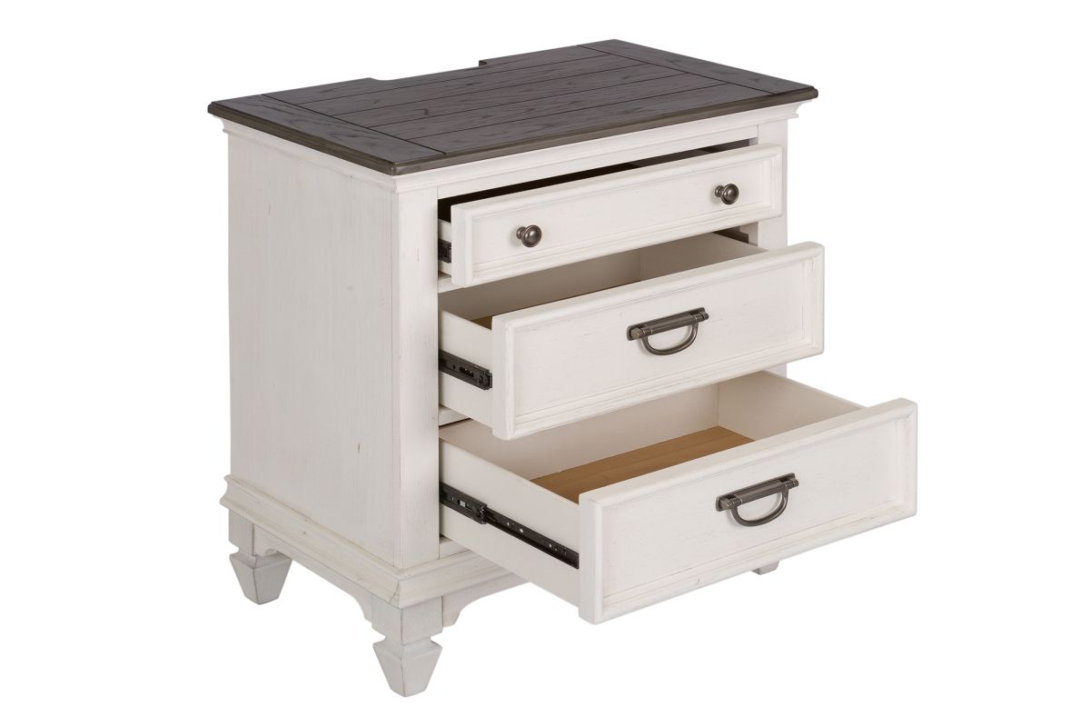 Corner view of a white wood nightstand with its three drawers opened